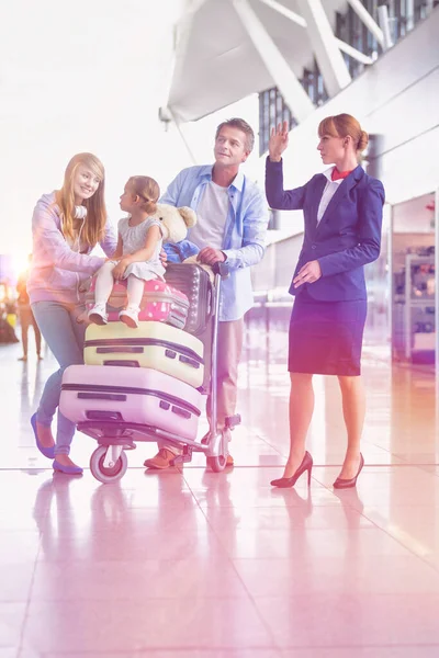 Family on holiday asking for assistance with airport staff in airport with lens flare in background