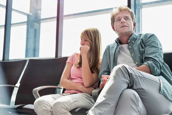 一个成熟的男人和他的女儿坐在一起 等待他们在机场的航班 — 图库照片