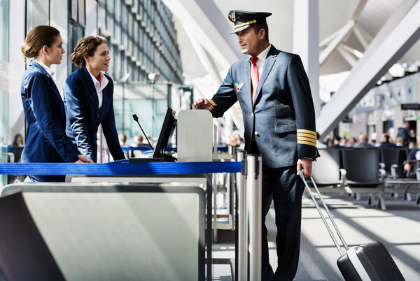 Portrait of mature pilot talking with the airport staffs in boarding gate