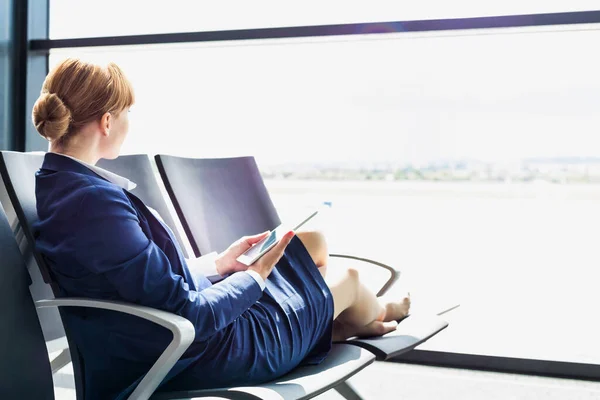 休憩中に椅子に座っている間にデジタルタブレットを使用して若い美しい空港スタッフ — ストック写真