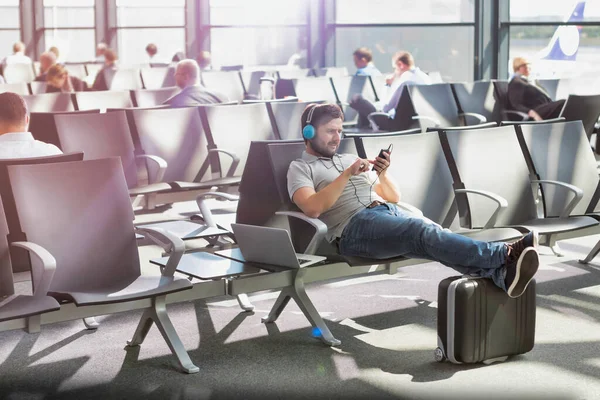 Retrato Del Hombre Usando Smartphone Con Auriculares Encendidos Mientras Espera — Foto de Stock