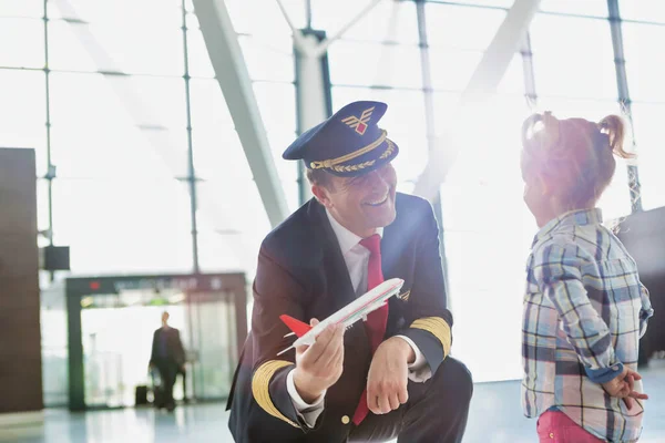 可愛いです女の子と一緒に空港で遊んでいる間成熟したパイロット保持飛行機おもちゃの肖像 — ストック写真