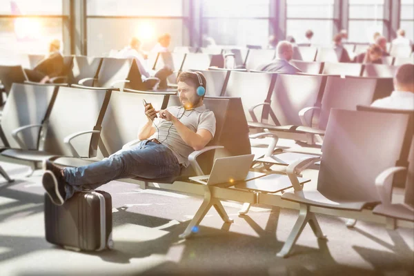 Retrato Del Hombre Usando Smartphone Con Auriculares Encendidos Mientras Espera — Foto de Stock