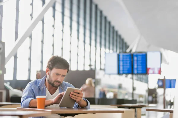 空港でのフライトを待っている間にデジタルタブレットを使用している男 — ストック写真