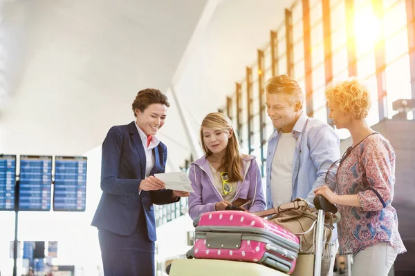 Family on holiday asking for assistance with airport staff in airport with lens flare in background