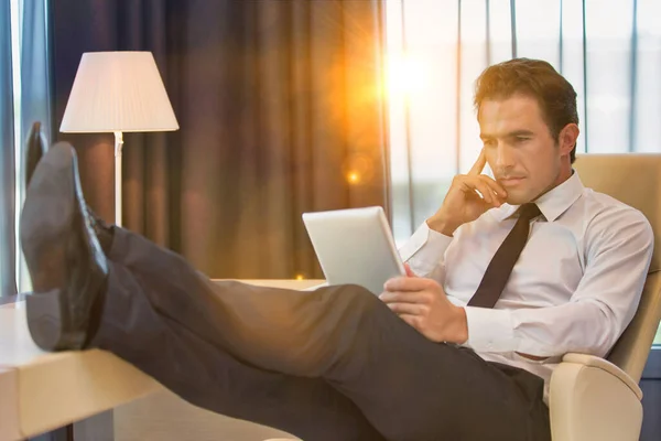 レンズフレアで座っている間にデジタルタブレットを使用して思慮深いビジネスマン — ストック写真