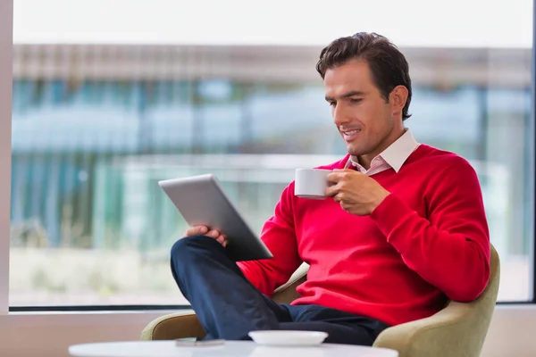 吸引人的商人坐在大堂喝咖啡时使用数码平板电脑的肖像 — 图库照片