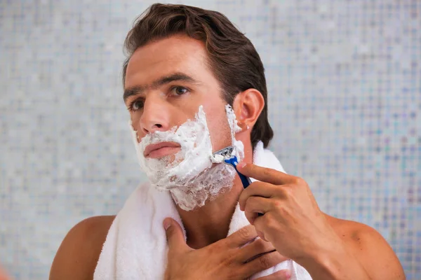 Retrato Jovem Atraente Homem Barbeando Sua Barba Enquanto Olha Espelho — Fotografia de Stock