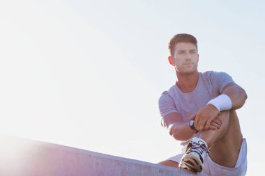 Genç, çekici, düşünceli bir adam oturuyor ve spor giysileri giyiyor.