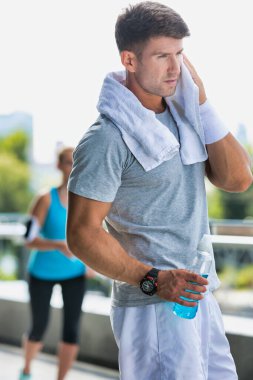 Enerji içeceği içerken ter silen genç çekici adamın portresi.