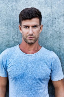 Duvarın önünde duran çekici genç adamın portresi.