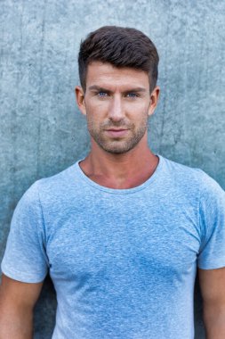 Duvarın önünde duran çekici genç adamın portresi.