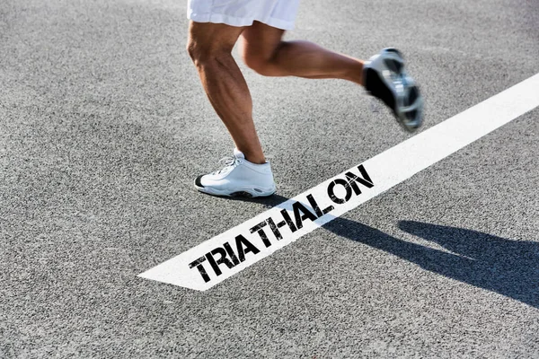 Mężczyzna Biegnie Białej Linii Znakiem Triathalon — Zdjęcie stockowe