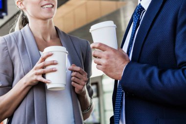 İş adamı ve iş kadınının portresi. Elinde kahve fincanı tutarken tren bekliyor.