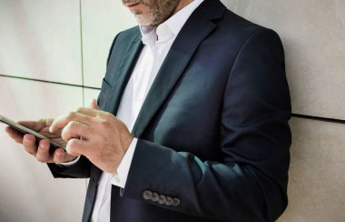 Duvara yaslanırken akıllı telefon kullanan işadamının portresi