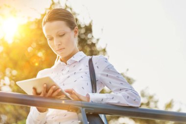 Tırabzanlara yaslanırken dijital tablet kullanan genç çekici iş kadını portresi