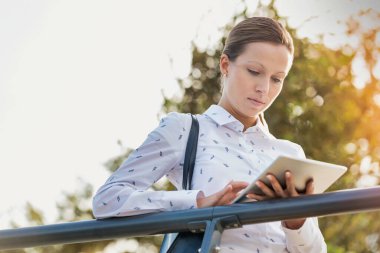 Tırabzanlara yaslanırken dijital tablet kullanan genç çekici iş kadını portresi