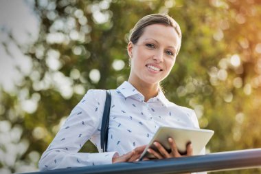 Tırabzanlara yaslanırken dijital tablet kullanan genç çekici iş kadını portresi