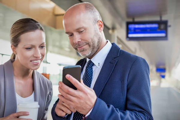 Tren Istasyonunda Genç Çekici Bir Kadınıyla Konuşurken Akıllı Telefon Gösteren — Stok fotoğraf