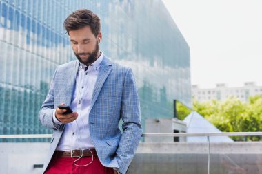 Kulaklıklı akıllı telefon kullanan genç çekici iş adamının portresi.