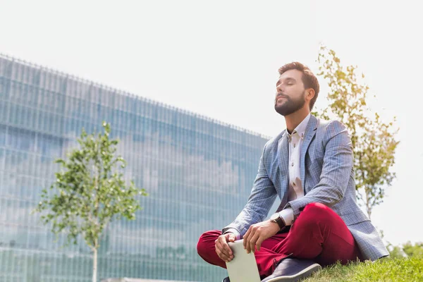 Young Thoughtful Businessman Sitting Grass While Holding Digital Tablet — Stock Photo, Image