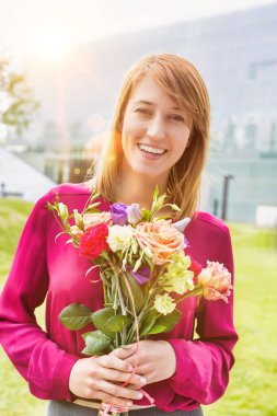 Elinde çiçek buketi olan çekici bir kadının portresi.