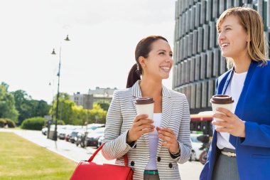 İş kadınları ofis binası dışında konuşurken yürüyorlar