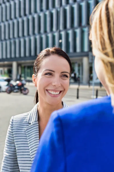 オフィスビルの外で話をしながら歩くビジネスマン女性 — ストック写真