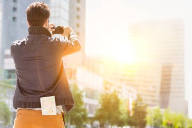 Genç ve çekici bir adam, arka planda lens ışığıyla şehrin güzel manzaralarını çekiyor.