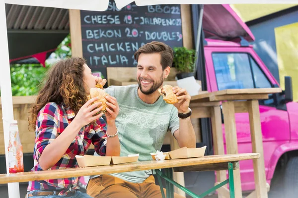 若いです魅力的なカップル食べるハンバーガーに対してフードトラック — ストック写真