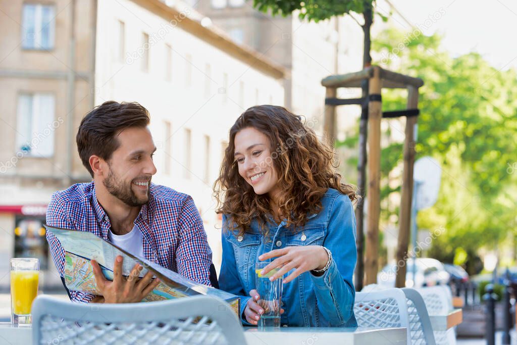 Young attractive couple smiling while looking at the menu in restaurant