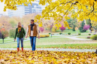 Olgun çift parkta yürürken sonbaharın tadını çıkarıyor.
