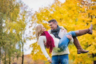 Yakışıklı, olgun bir adamın parkta yürürken karısını taşıyan portresi.