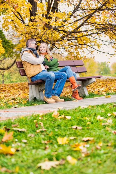 公園で彼の美しい妻と話をしながら 魅力的な男の肖像画はベンチに座って — ストック写真
