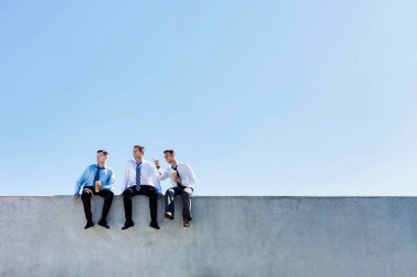 Düşünceli iş adamlarının çatıda oturup rahatlarken çekilmiş bir fotoğrafı.