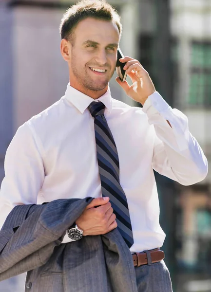 成熟した自信のあるビジネスマンの笑顔の肖像画や舗装を歩いている間にスマートフォンで話して — ストック写真
