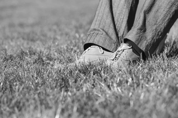 草の上のビジネスマンの足の黒と白の写真 — ストック写真