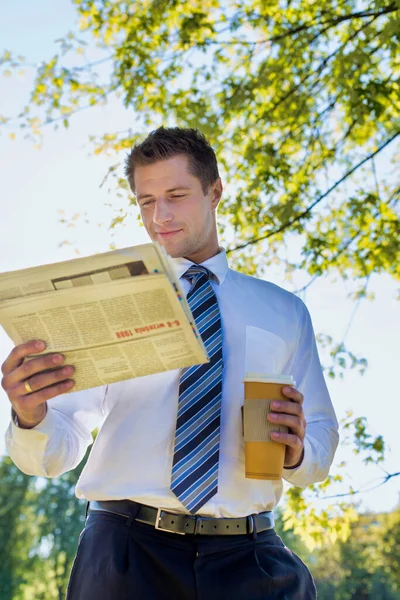休憩中に公園で新聞を読んでいる間にコーヒーのカップを保持ハンサムな成熟したビジネスマンの肖像画 — ストック写真