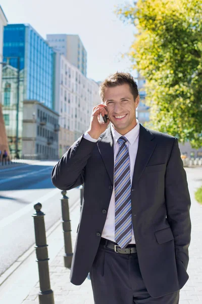 成熟自信的商人在人行道上行走时微笑着 用智能手机交谈的肖像 — 图库照片
