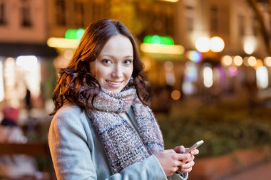 Akıllı telefon kullanırken gülümseyen çekici bir kadının portresi