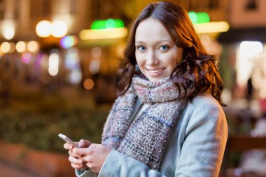 Akıllı telefon kullanırken gülümseyen çekici bir kadının portresi