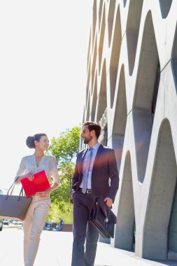 İş adamı ve iş kadını buluşmadan önce planlarını tartışırken yürüyorlar