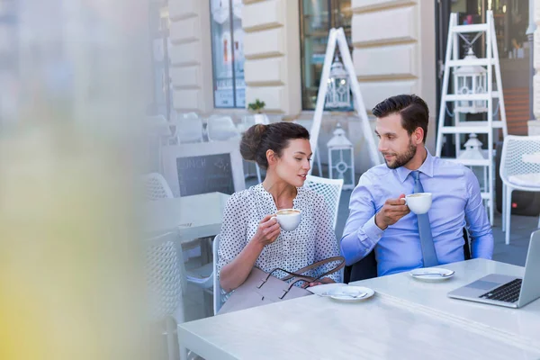 Businesswoman discussing plans with businessman while having coffee during office break