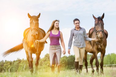 Çiftlikte atlarıyla konuşurken gezen öğretmen ve öğrenci portresi.