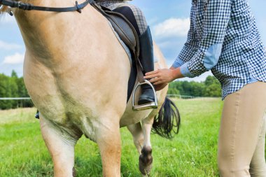 Yetişkin bir kadının genç kadın ayaklarını üzengi demiriyle kapattığı fotoğraf.