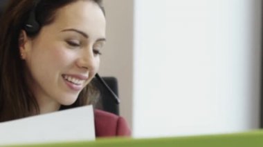 Çağrı merkezinde kulaklıkla konuşan çekici bir iş kadını.