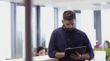 Sakallı Çekici İşadamı, ofiste tablet bilgisayar kullanarak çalışıyor.