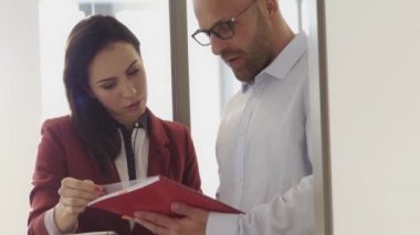 İş adamı ve işkadını büroda kırmızı dosya üzerinde konuşuyorlar.