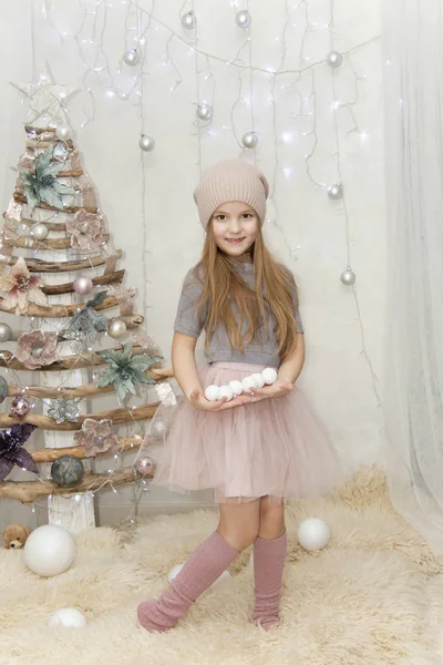 joyful girl with spheres costs near a fur-tree