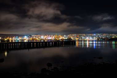 Gece Murmansk, körfeze yansıyan şehir ışıkları ve limanda duran gemiler.